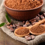 Cocoa powder and cocoa beans on wooden background