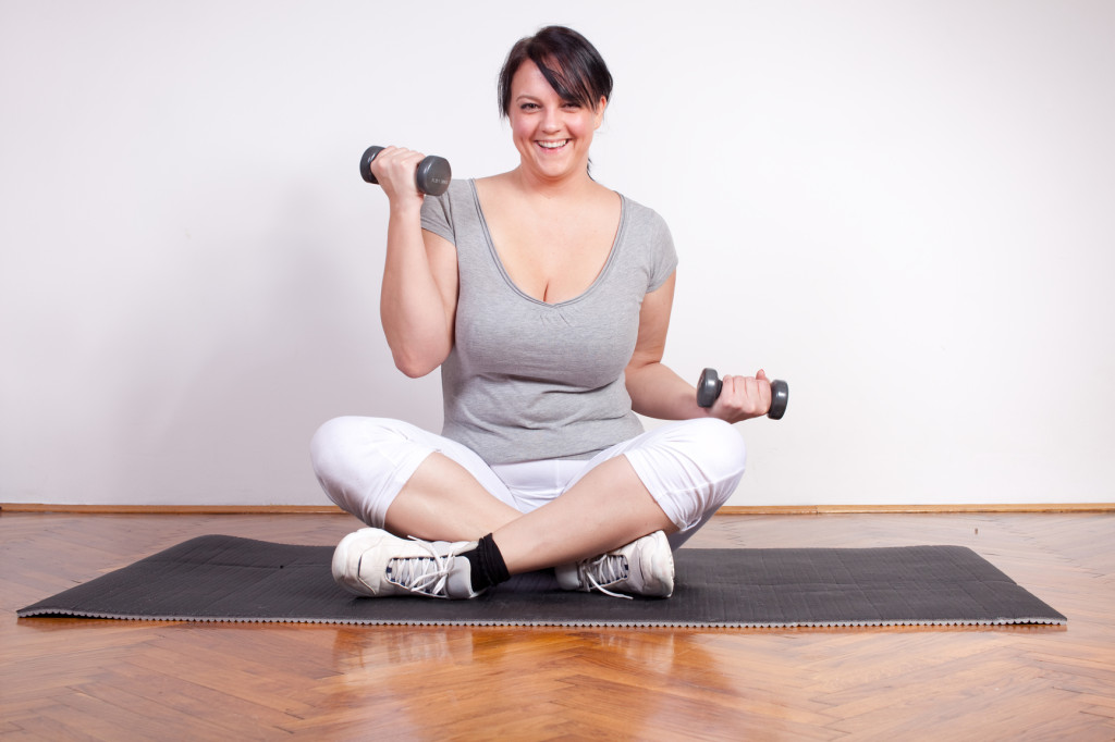 Happy overweight woman lifting weights