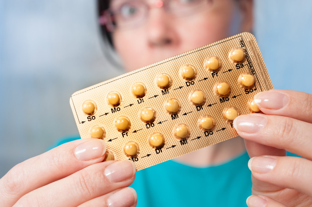 Birth control pills in hands of young woman