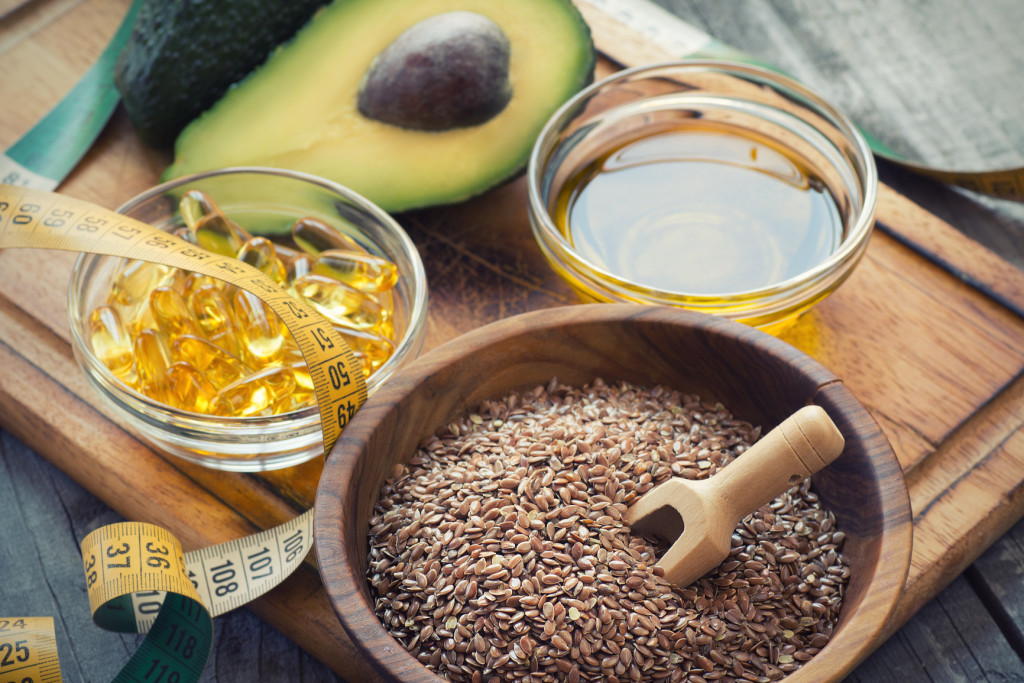 Sources of omega 3 fatty acids: flaxseeds, avocado, oil capsules and flaxseed oil