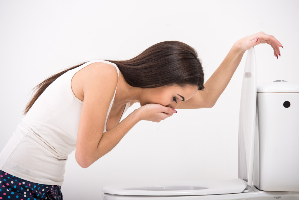 Young woman vomiting into the toilet bowl 